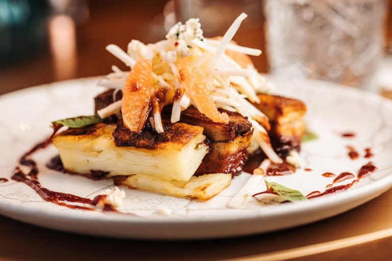 A dish with glazed pork belly, shredded apple & celeriac and blue cheese