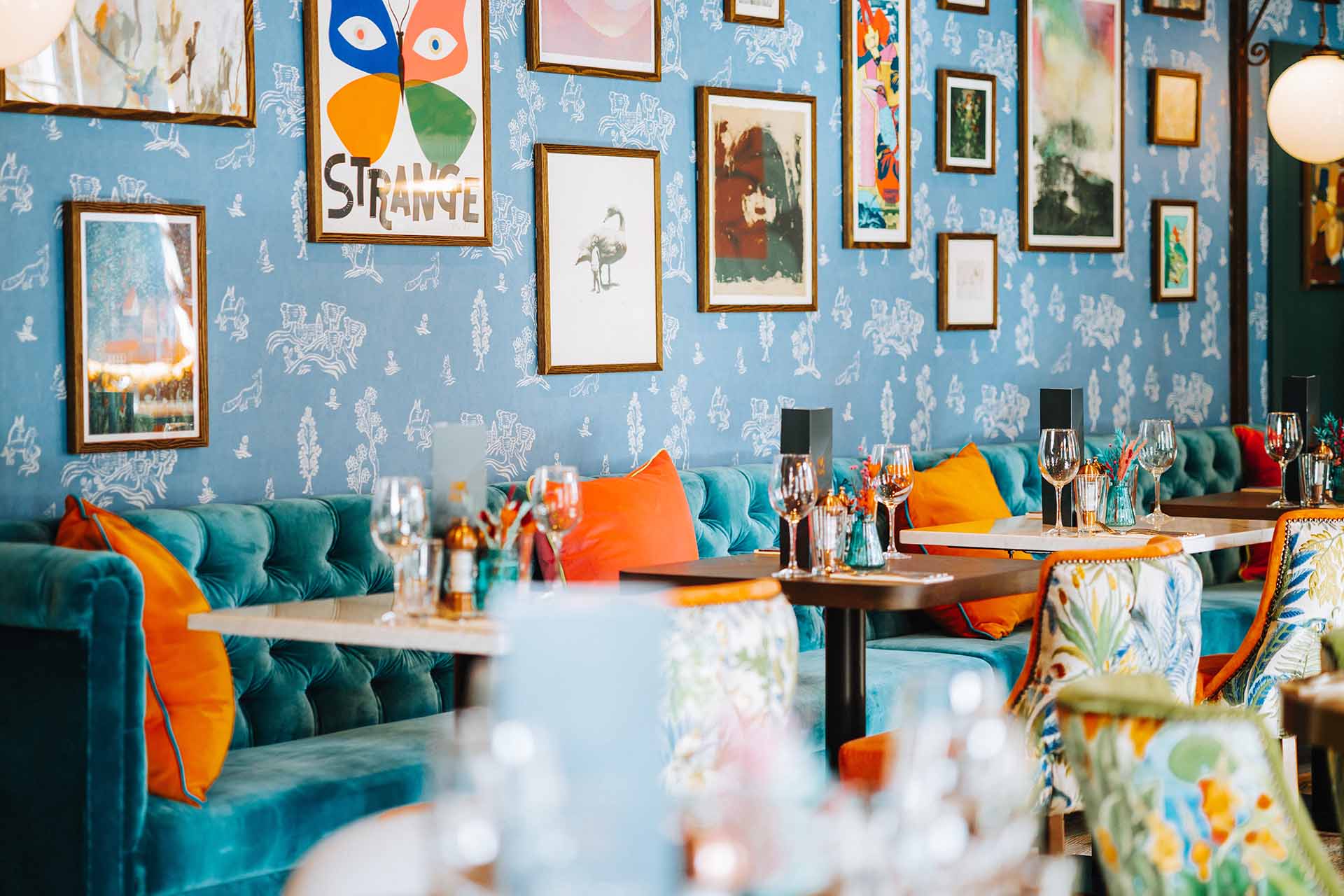 Interiors with blue and orange design, blue wallpaper and framed art on the walls